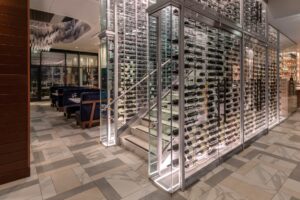 Del Frisco's Double Eagle Steakhouse San Diego displays wine bottles in transparent glass racks build into walls lining a staircase