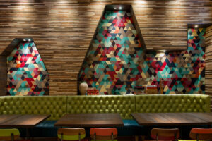 Wood-faced walls are set off by colorful cutout details at Nando's Lakeview location in Chicago, IL