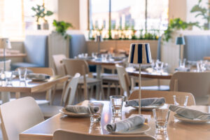 A table is set at Saltwater Coastal Grill. Blue accents are mixed in with the beachy white decor