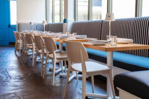 Booths and windows line the walls of Saltwater Coastal Grill in Rosemont, IL. The booths are striped with white and blue, and the minimal decor is a beachy white