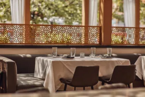 A long table and soft bench seating backed by a decorative screen divider